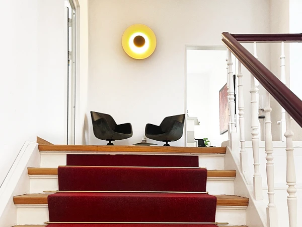 Moderne Treppe mit rotem Teppich, zwei Sessel im Hintergrund