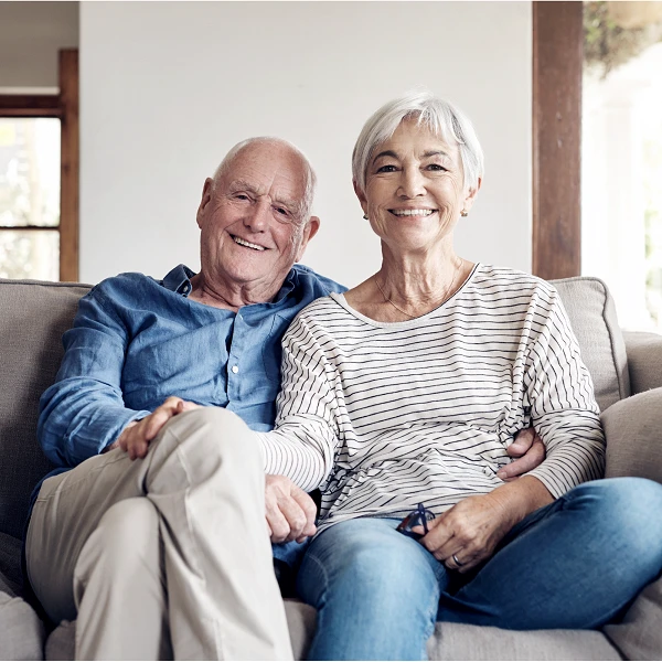 Älteres Paar auf Sofa, Arm in Arm, freundlich lächelnd